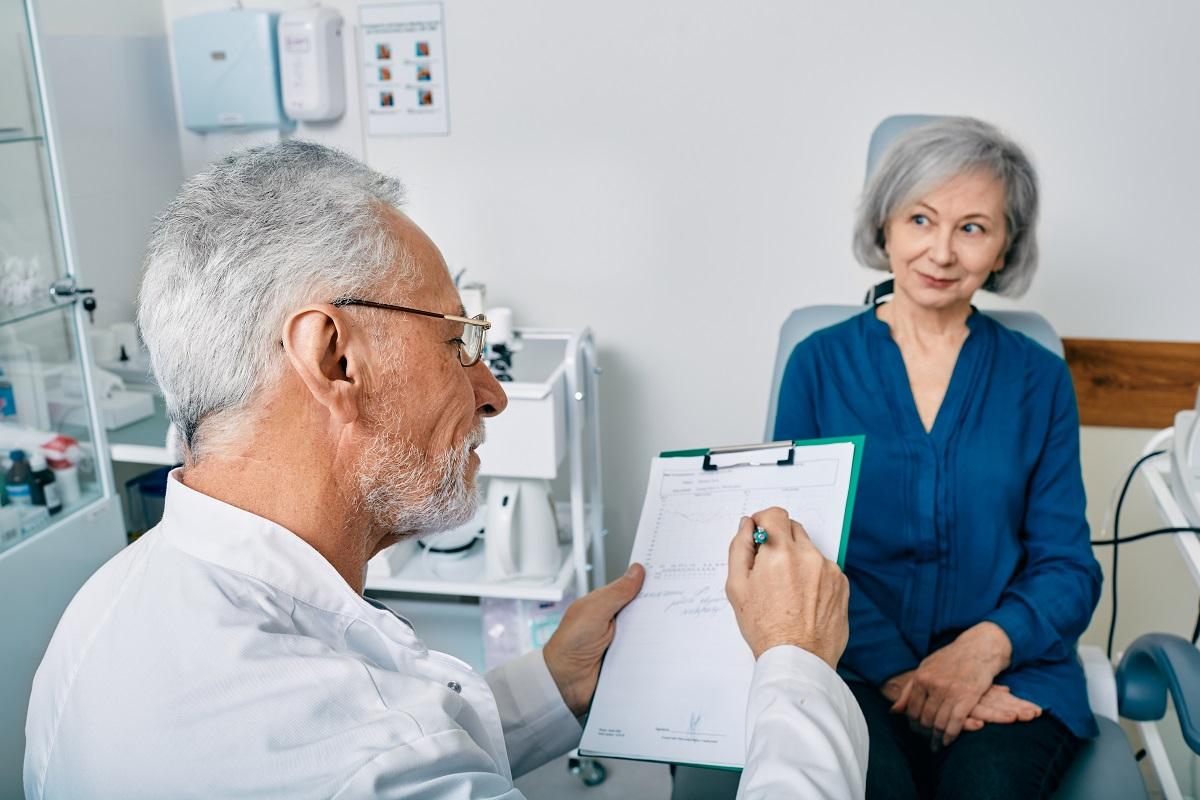 Audiologist writing on patient chart with patient during hearing exam