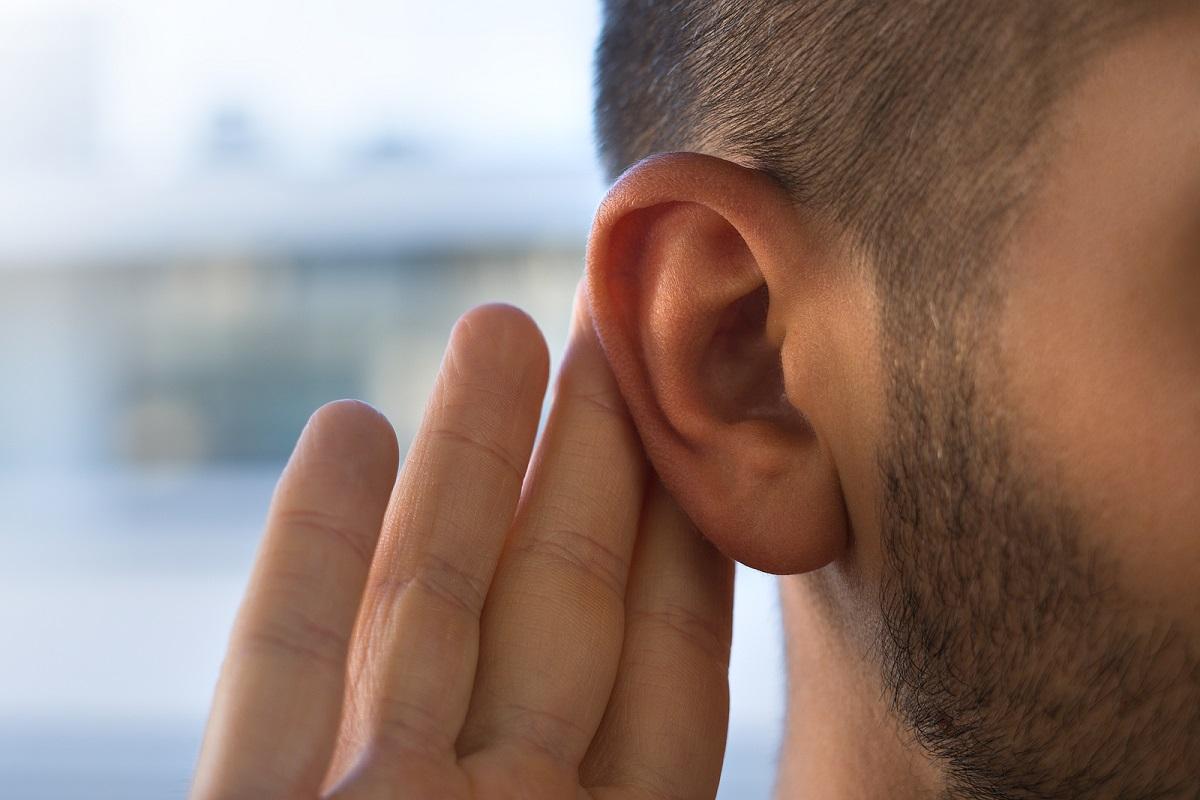 Close up of man's ear with hand behind it