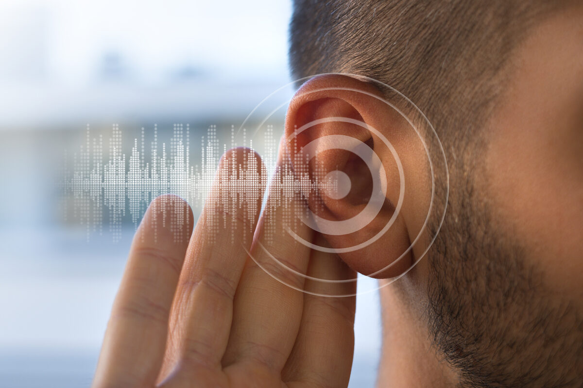 Close up of man's ear with hand behind it