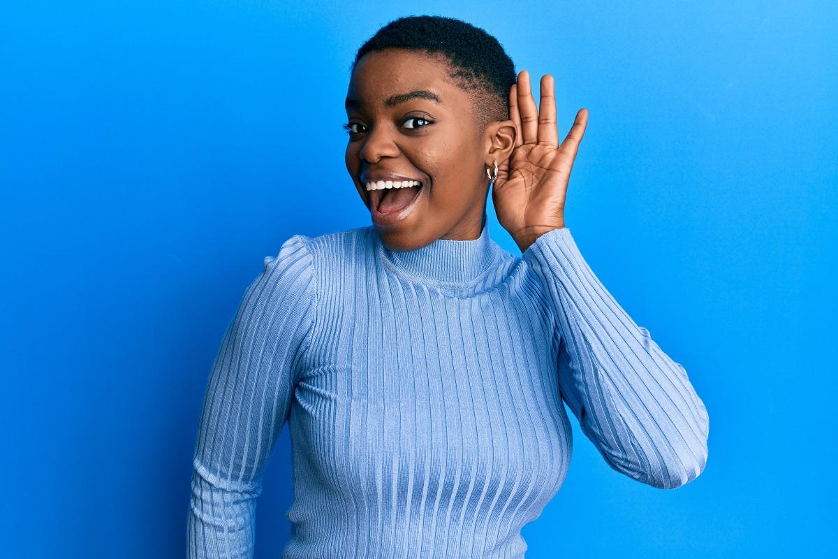 Young woman smiling and cupping her hand behind her ear