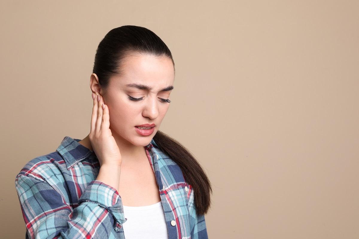 Young woman holding her hand up to her ear in pain