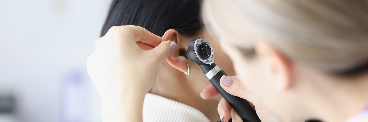 Close-up Of Female Otolaryngologist Examining Ear With Otoscope.
